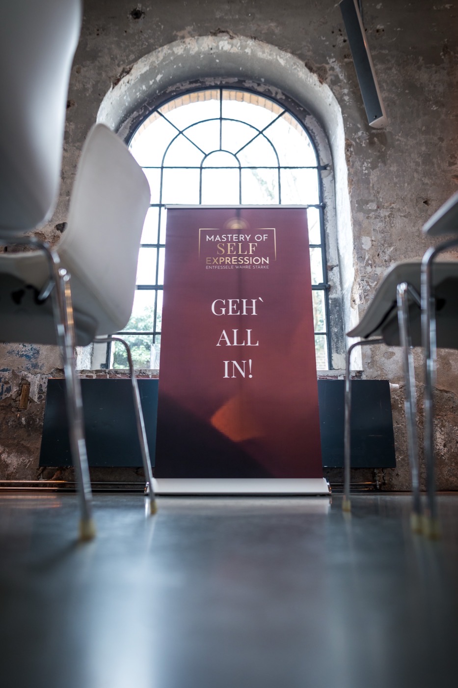 Seminarraum der Mastery of Self Expression mit dem Banner „Geh all in!“